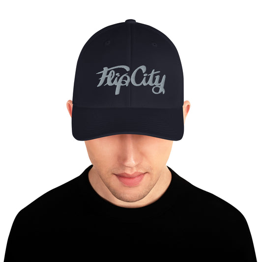 A man wearing a black structured twill cap with 'Flip City' embroidery on the front.